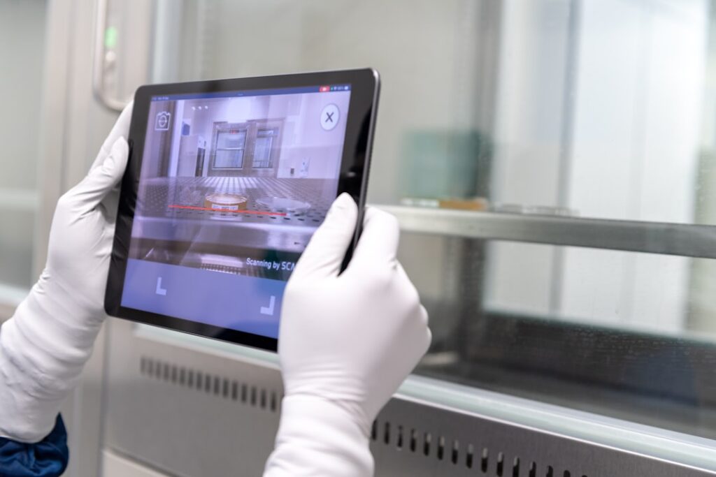 A person scanning a barcode on a petri dish us a tablet.